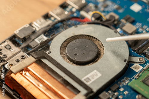 A technician repairs a broken laptop computer with a screwdriver. Notebook components and parts close-up