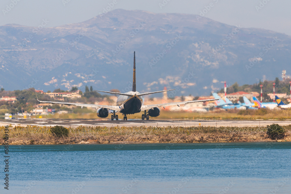 Fototapeta premium View of modern passenger plane aircraft on an runway airfield ready to take off, airstrip with commercial airplane before take off or after landing, airliner with mountains in a summer day