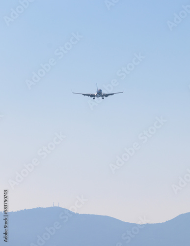 View of modern passenger plane aircraft in flight  commercial airplane flying in the sky before take off or landing  with mountains in the background in a summer sunny day
