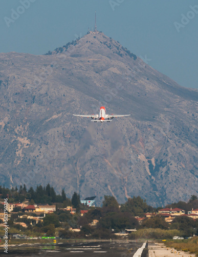 View of modern passenger plane aircraft in flight, commercial airplane flying in the sky before take off or landing, with mountains in the background in a summer sunny day