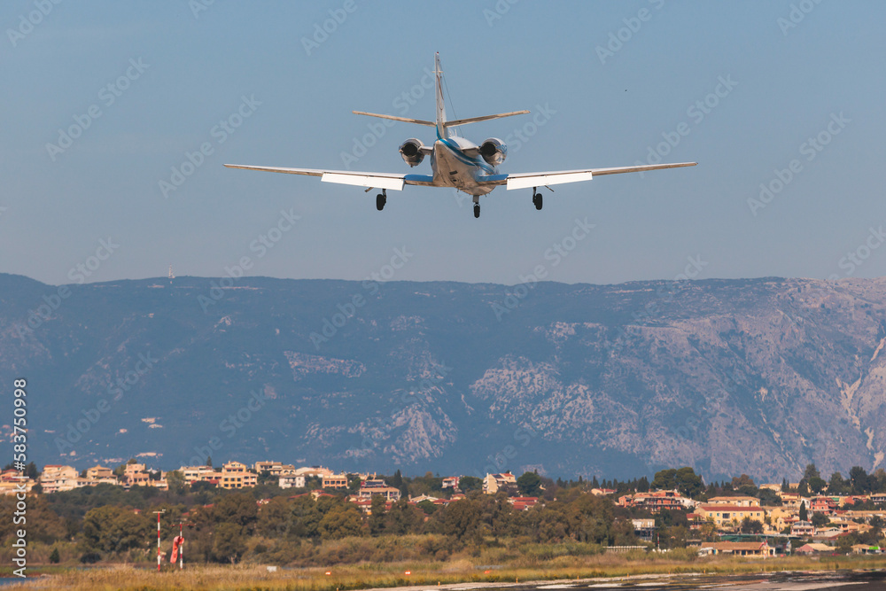 Fototapeta premium View of modern private reactive plane aircraft in flight, business airliner jet airplane before in the air with mountains in the background in a summer sunny day, corporate jet view