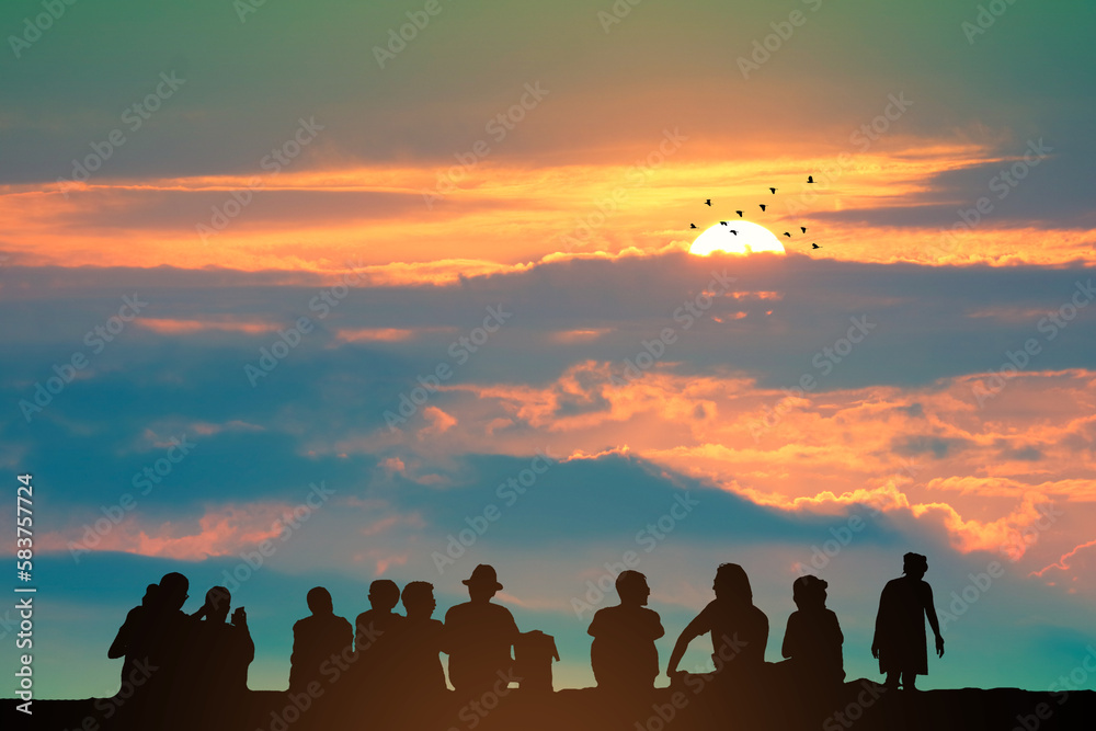 Fototapeta premium Silhouette people sitting on the top mountain and sunset on the colorful sky orange cloud and birds flying