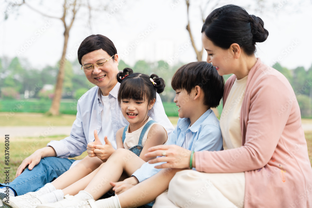 image of an asian family sitting together on the grass at the park image of an asian family sitting together on the grass at the park