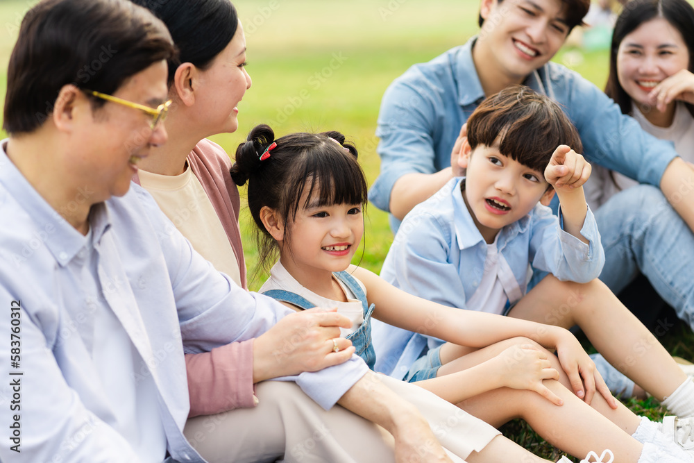 image of an asian family sitting together on the grass at the park image of an asian family sitting together on the grass at the park