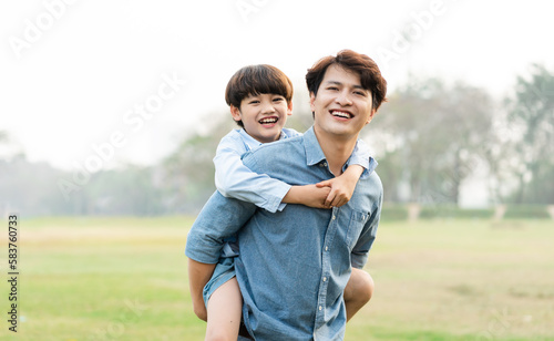 image of an asian father and son having fun in the park photo