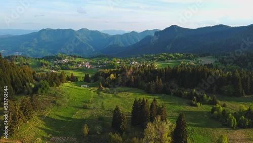 Mountain valley sheltered by vegetation and spruce forests with village of Smolyan with meadows where sheep graze photo