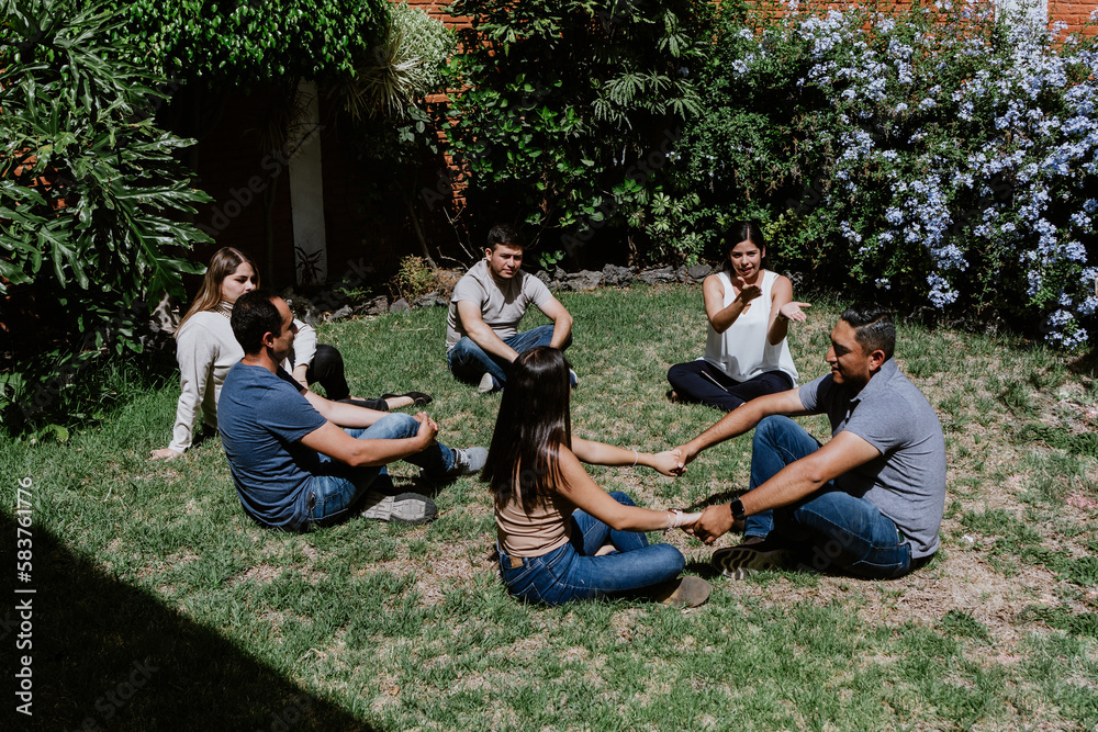 hispanic young people seated in circle on grass and participating at group therapy session in Mexico Latin America