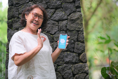 Woman showing smartphone accessing Satusehat, in Yogyakarta 20 February 2023 photo