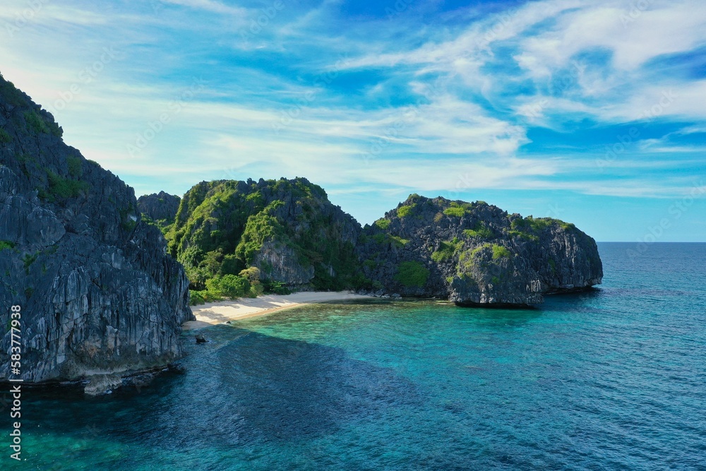 Panorama drone shot of the paradisiacal beach of Coron, Palawan in the Philippines with fine white beach, palm trees and majestic rocks. Panorama drone shot of the paradisiacal beach of Coron, Palawan in the Philippines with fine white beach, palm trees and majestic rocks.