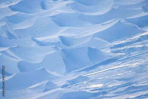 Snow texture. Wind sculpted patterns on snow surface. Wind in the tundra and in the mountains on the surface of the snow sculpts patterns and ridges (sastrugi). Arctic, Polar region. Winter background