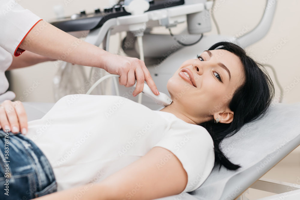 Ultrasound diagnosis of the thyroid gland of a young woman in the clinic. A female doctor holds an ultrasound probe along the patient's neck. Health concept. Ultrasound diagnosis of the thyroid gland of a young woman in the clinic. A female doctor holds an ultrasound probe along the patient's neck. Health concept.