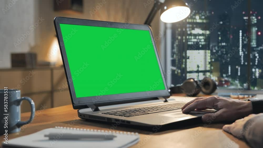 using laptop computer green screen on desk at night in modern home office,hand touching notebook touchpad,chroma key display