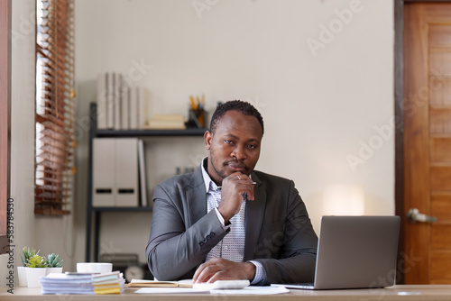 Tired American African business man in stress works with many paperwork document. migraine attack. Freelance, work from home © itchaznong
