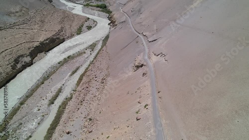 aerial top down of an alsphalt road on a steep dry rugged mountain terrain with Spiti River flowing through the valley on a sunny summer day photo