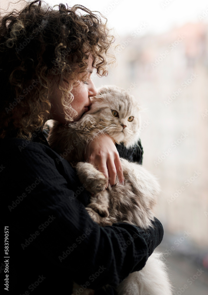 Woman with cat standing near the open window