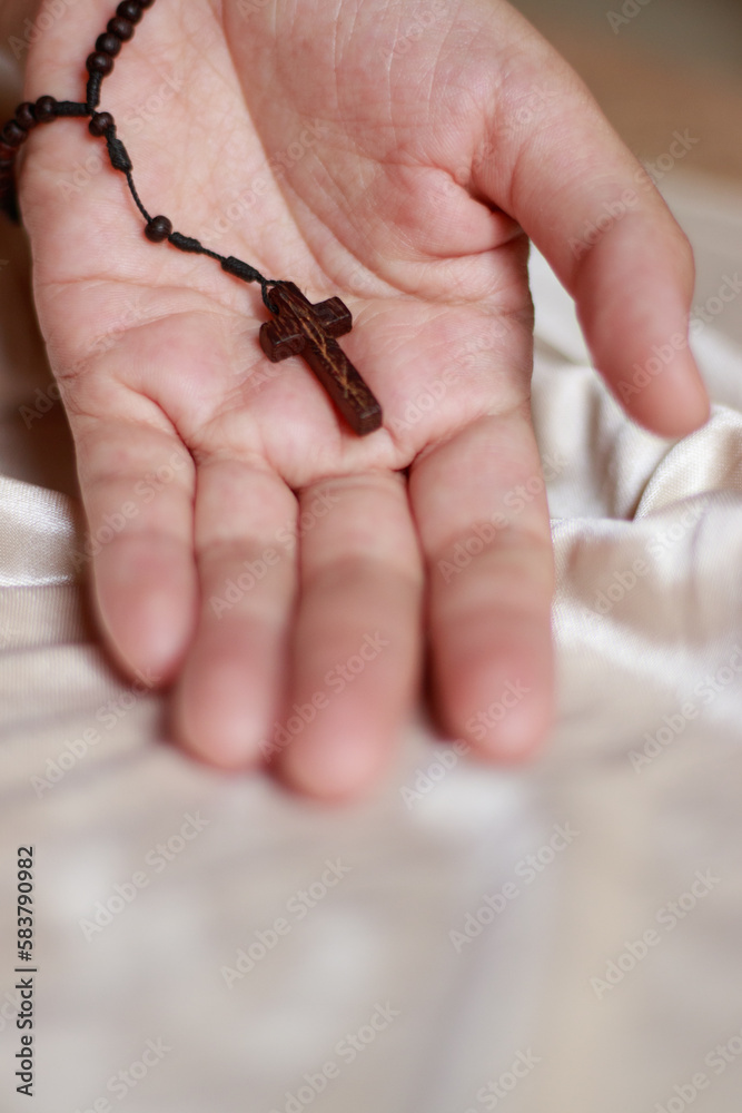 A wooden rosary and crucifix on an open palm of a hand representing lent, solemn Christian religious observance A wooden rosary and crucifix on an open palm of a hand representing lent, solemn Christian religious observance