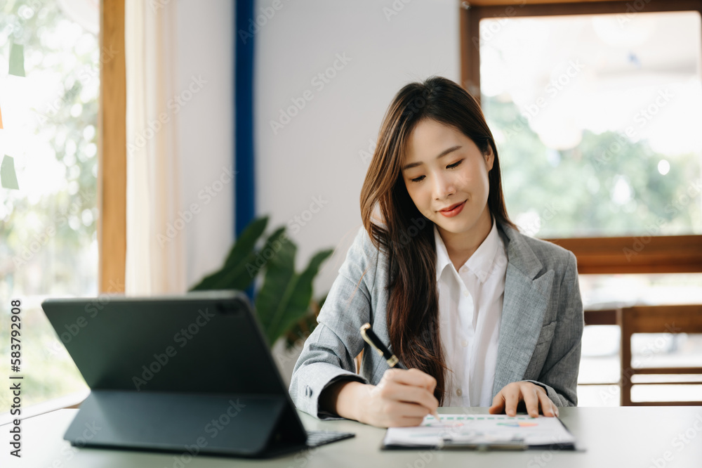 Young beautiful woman using laptop and tablet while sitting at her working place. Concentrated at work... Young beautiful woman using laptop and tablet while sitting at her working place. Concentrated at work...