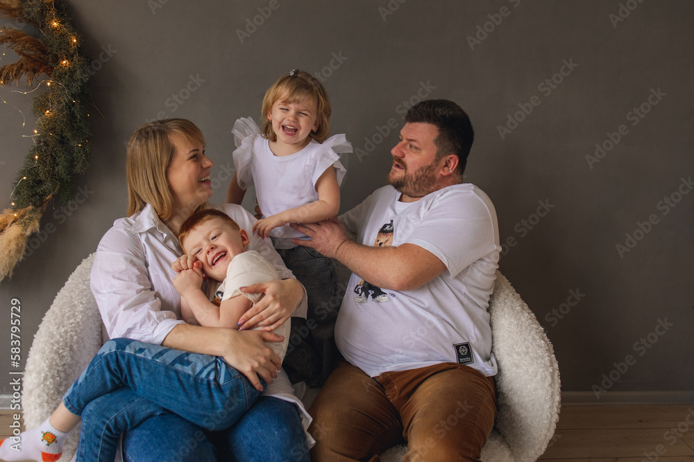 Family photo session in the studio. Happy family of four: mom, dad, son and daughter. 
