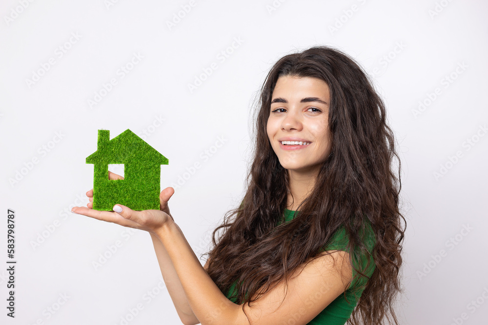 Happy house buyer. A young girl holds a model of a green house in her hands. The concept of green energy, ecology. Happy house buyer. A young girl holds a model of a green house in her hands. The concept of green energy, ecology.