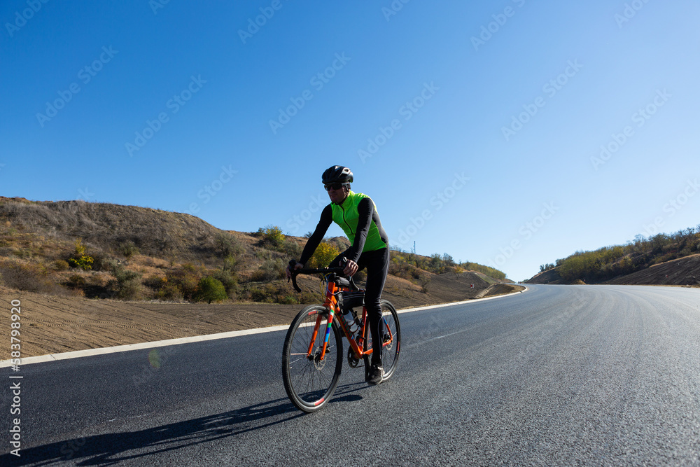 Cyclist riding bicycle on road against clear sky