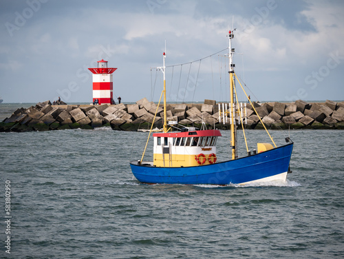 Fishing boat and northern pier with red white beacon of Scheveningen harbor, The Hague, Netherlands