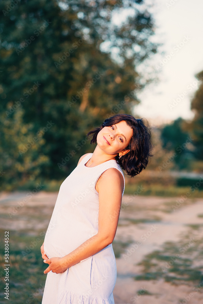 Happy pregnant woman relaxing and enjoying life in nature sunlight of sunset. concept of Mother's Day and Women's Day. Close-up of pregnant woman with hands on her belly. Pregnancy, maternity. Happy pregnant woman relaxing and enjoying life in nature sunlight of sunset. concept of Mother's Day and Women's Day. Close-up of pregnant woman with hands on her belly. Pregnancy, maternity.
