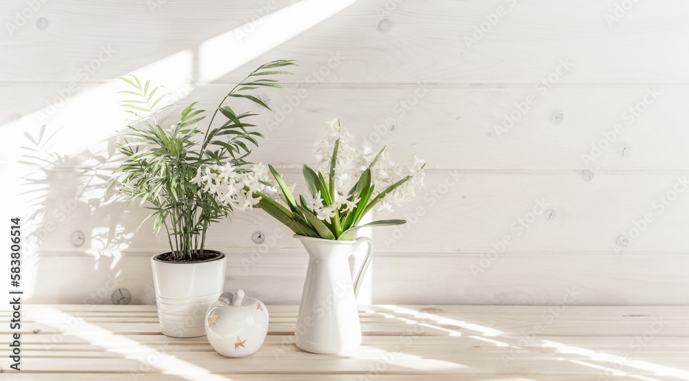 Home interior with Easter decor. Spring flowers in a vase, indoor plant on the background of a wooden white wall Home interior with Easter decor. Spring flowers in a vase, indoor plant on the background of a wooden white wall