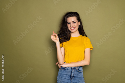 Young girl is posing in close pose with arms crossing on chest on khaki background