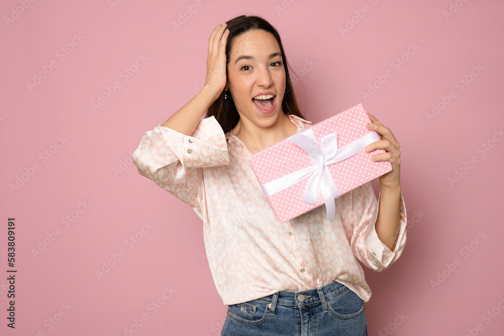 Close-up portrait of happy exited pretty brunette woman holding gift box, looking at camera, isolated on pink background Close-up portrait of happy exited pretty brunette woman holding gift box, looking at camera, isolated on pink background
