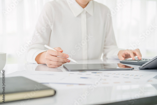 Modern business woman using calculator and tablet in workstation.