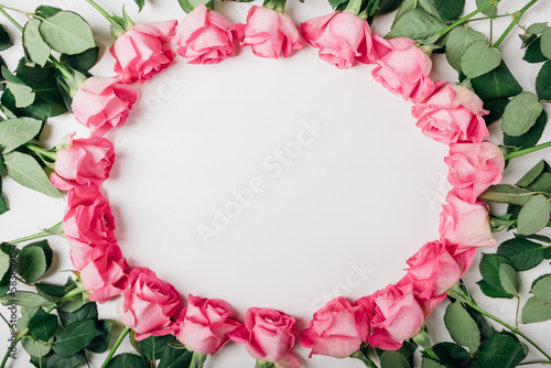 Fototapeta Naklejka Na Ścianę i Meble -  Frame of fresh pink roses in full bloom on white background. Bunch of flowers with negative space for text. Top view, flat lay. Valentine's day or Mother's day card.