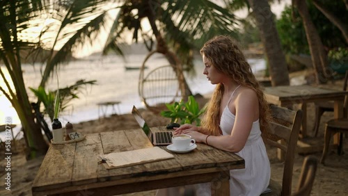 Wallpaper Mural Female crypto trader at laptop checking candlestick charts online working remotely at outdoor tropical seaside cafe. Woman broker analyses exchange rates and bets on crypto stock by ocean closeup Torontodigital.ca