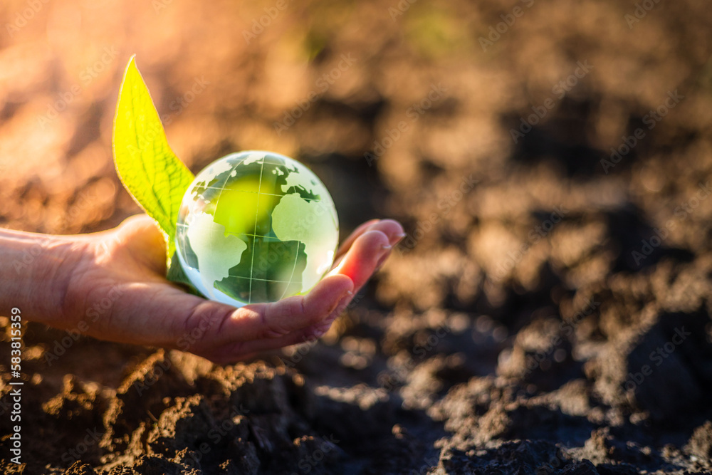 Hand holding glass Earth globe over dry soil. Earth Day environment ...