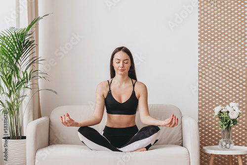 A young woman sits in a lotus position and meditates. Yoga classes at home Free Download A young woman sits in a lotus position and meditates. Yoga classes at home - GFXLoad