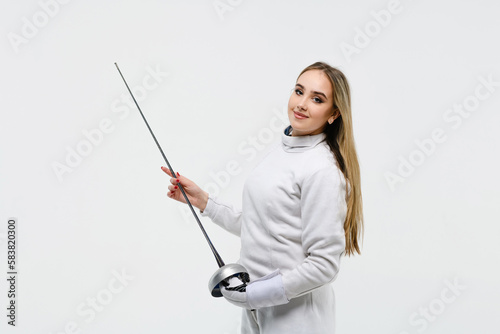 Teen girl in fencing costume with sword in hand on white background