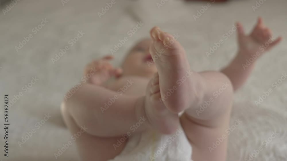 Adorable closeup of Caucasian baby feet and fingers, playful newborn in white sheets Adorable closeup of Caucasian baby feet and fingers, playful newborn in white sheets