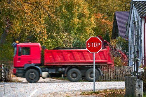 A large red delivery truck driving past a stop sign