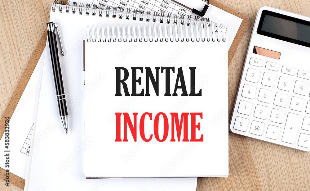 RENTAL INCOME is written in white notepad near a calculator, clipboard and pen. Business concept RENTAL INCOME is written in white notepad near a calculator, clipboard and pen. Business concept