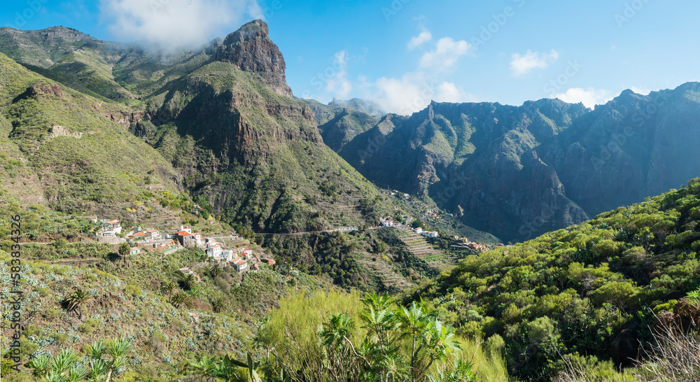 Panoramic view of Mirador de Cruz de Hilda. Picturesque valley with old village El turron. Landscape of sharp rock formation, green hills and cliffs. Tenerife, Canary Islands, Spain. sunny winter day,