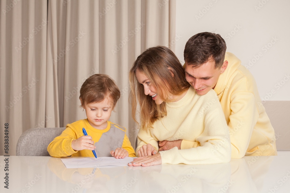Adorable smiling family, parents in yellow clothes with their son painting Adorable smiling family, parents in yellow clothes with their son painting