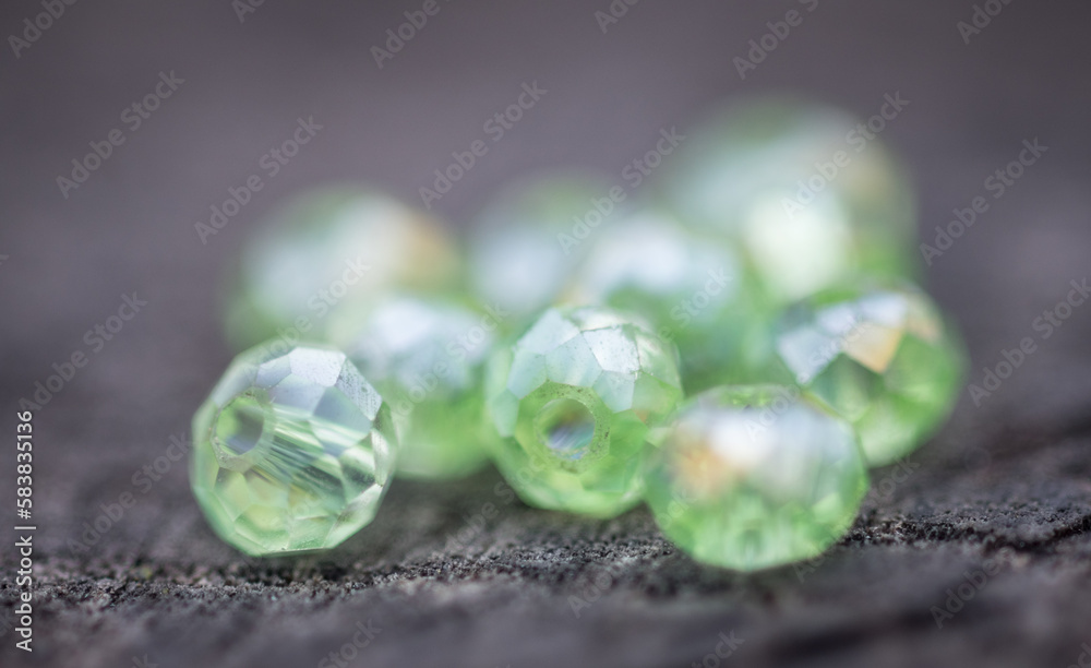 Glass beads of various shapes and sizes are photographed on a wooden board of neutral color. Glass beads of various shapes and sizes are photographed on a wooden board of neutral color.