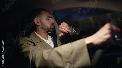 One anxious man driving at night holding steering wheel. Nervous expression of a Middle Eastern male person late on road photo