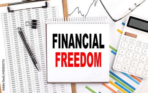 FINANCIAL FREEDOM text on notebook with chart, calculator and pen