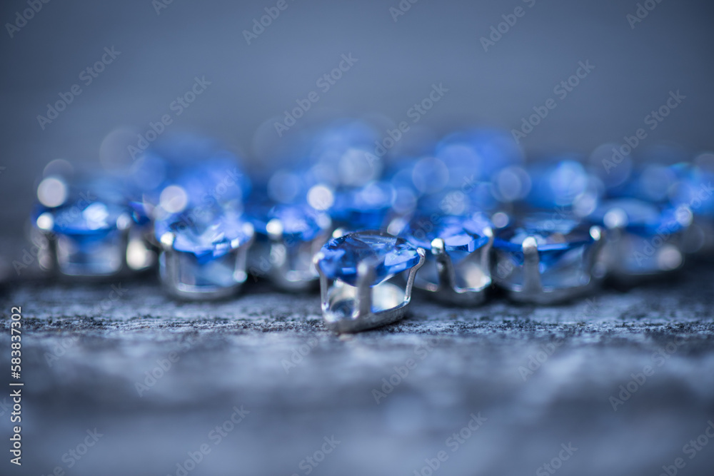 Rhinestones of various sizes and shapes are fixed in goats of gold and silver color, photographed on a wooden board of neutral color. Rhinestones of various sizes and shapes are fixed in goats of gold and silver color, photographed on a wooden board of neutral color.