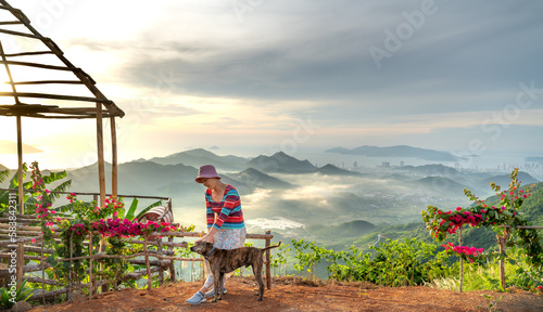 A female tourist plays with her two pet dogs on a high mountain in Nha Trang city, Khanh Hoa province, Vietnam