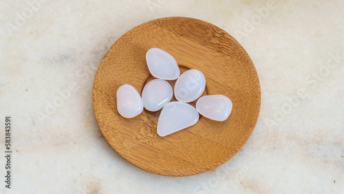 Little white transparent stones on wooden plate. photo