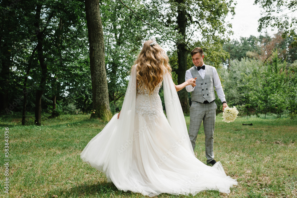 The bride and groom walk after wedding ceremony. A newlyweds couple walking in a country. photo on nature, forest, outdoors.