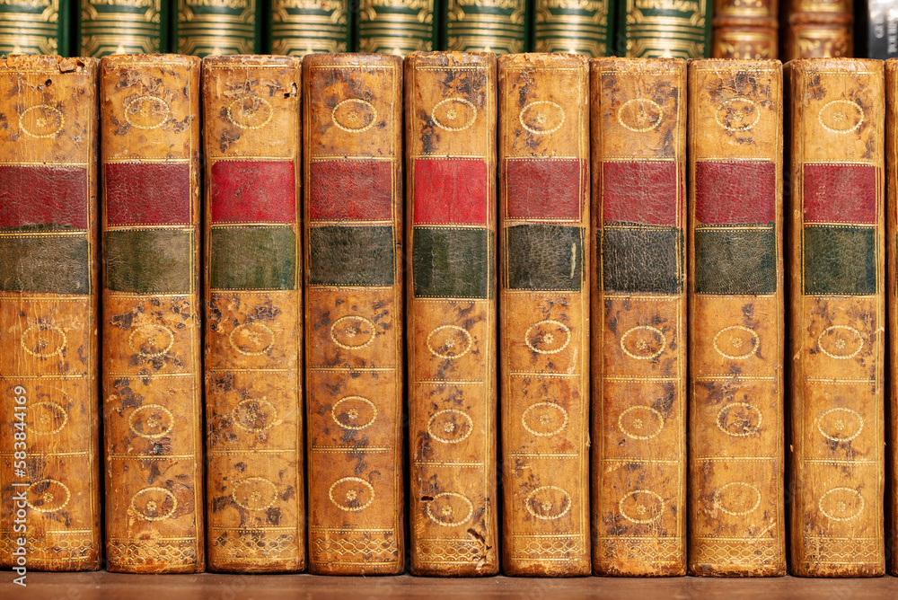 Pile of antique books with a leather cover and golden ornaments on a wooden table Pile of antique books with a leather cover and golden ornaments on a wooden table