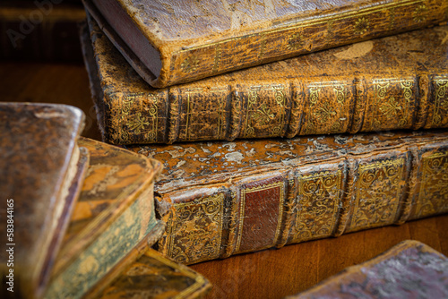 Pile of antique books with a leather cover and golden ornaments on a wooden table © Maxal Tamor