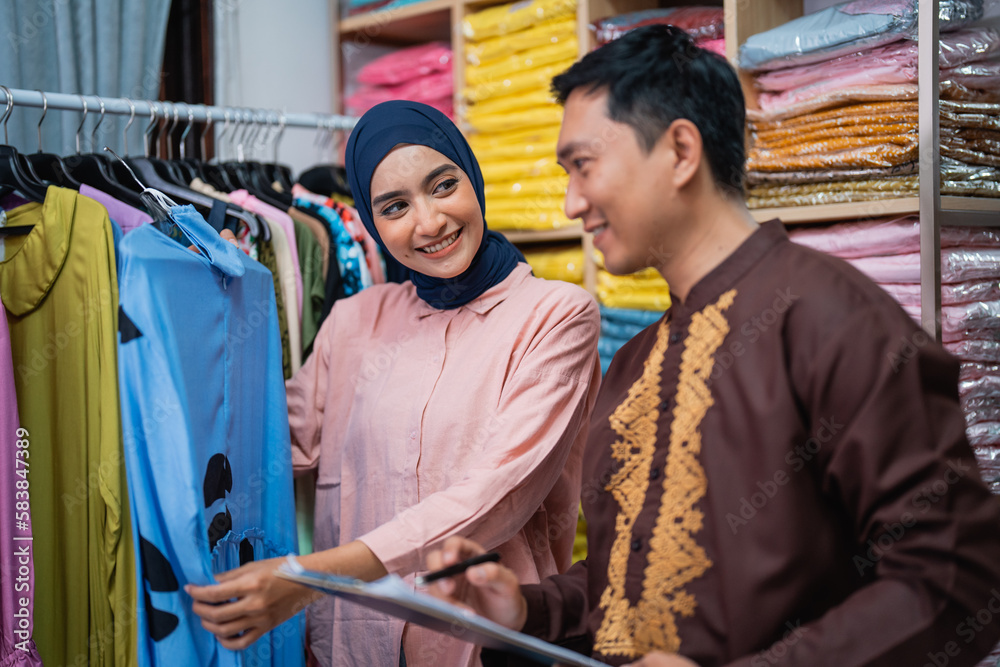 asian muslim woman and man checking their fashion product at the shop